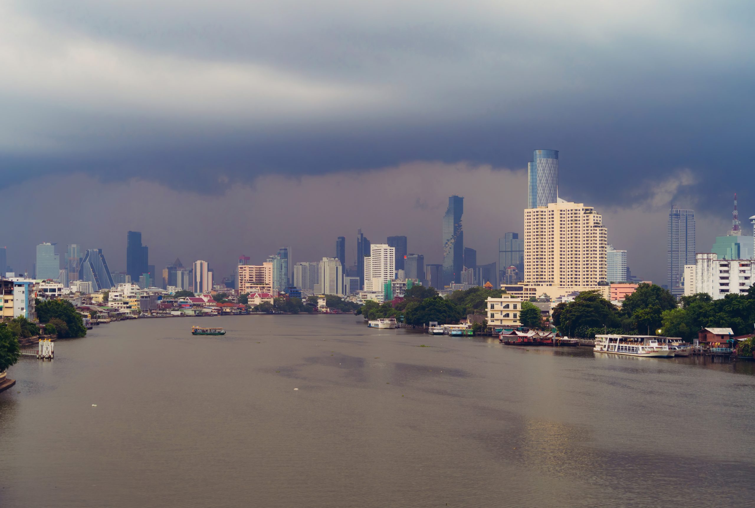 Taksin Bridge with Chao Phraya River, Bangkok Downtown. Thailand. Financial district and business centers in smart urban city. Skyscraper and high-rise buildings with storm rain.