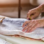Male hand on raw fish.
